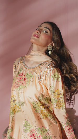 Video of model showcasing Leni sheesha silk semi‑formal set in peach with floral block print and embellished neckline, styled with matching pants and lace‑finished dupatta.
