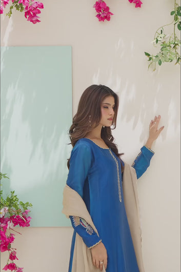 VIDEO: A model presents a formal blue ensemble featuring traditional floral embroidery and a contrasting beige dupatta accented with colorful thread motifs.
