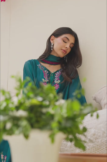 VIDEO: Video of a model showcasing the fit, movement, and intricate floral embroidery details of a teal green traditional long shirt and dupatta set.
