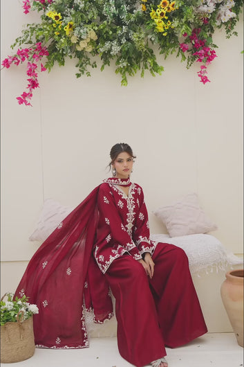 Video Alt Text: Fashion showcase video featuring a model modeling a deep red traditional three-piece suit with white floral embroidery.
