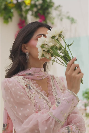 VIDEO: A woman poses in a soft pink traditional ensemble featuring floral embroidery, sheer puff sleeves, and wide-leg trousers.
