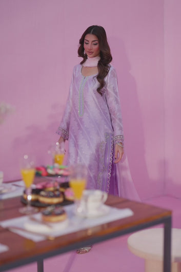 A video of Zunaira Teli’s "Kiya": Close-up shows lilac silk dupatta trim with floral and geometric embroidery, a modern detail against a pink backdrop.
