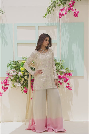 VIDEO: Model posing in a three-piece beige suit featuring a sheer embroidered shirt, silver lace borders, and flared ombre pants.
