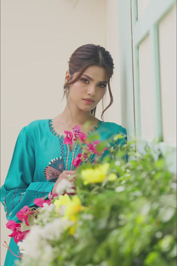 VIDEO: Video showcasing a model wearing a flowing silhouette and intricate multi-colored embroidery details of a turquoise traditional long dress.
