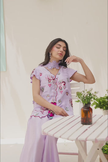 VIDEO: Video showing a model modeling a lilac ethnic co-ord set with a floral embroidered scalloped tunic and wide-leg trousers from multiple angles.
