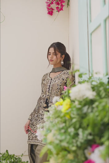 VIDEO: Video showcasing a model modeling a luxury olive-green embroidered traditional suit with a draped black dupatta.
