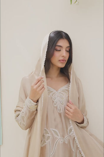 Video: A model showcases a beige silk traditional outfit with intricate white floral embroidery, draping a matching dupatta.
