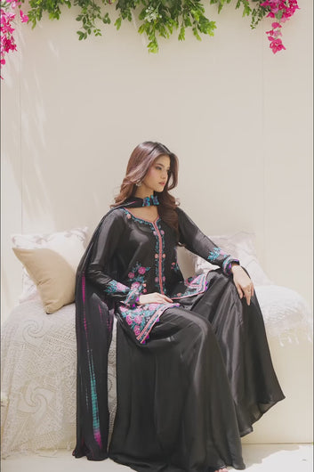 VIDEO: A model showcases a black formal ensemble featuring vibrant pink and turquoise floral embroidery, paired with wide-leg trousers and a coordinating tie-dye print dupatta.
